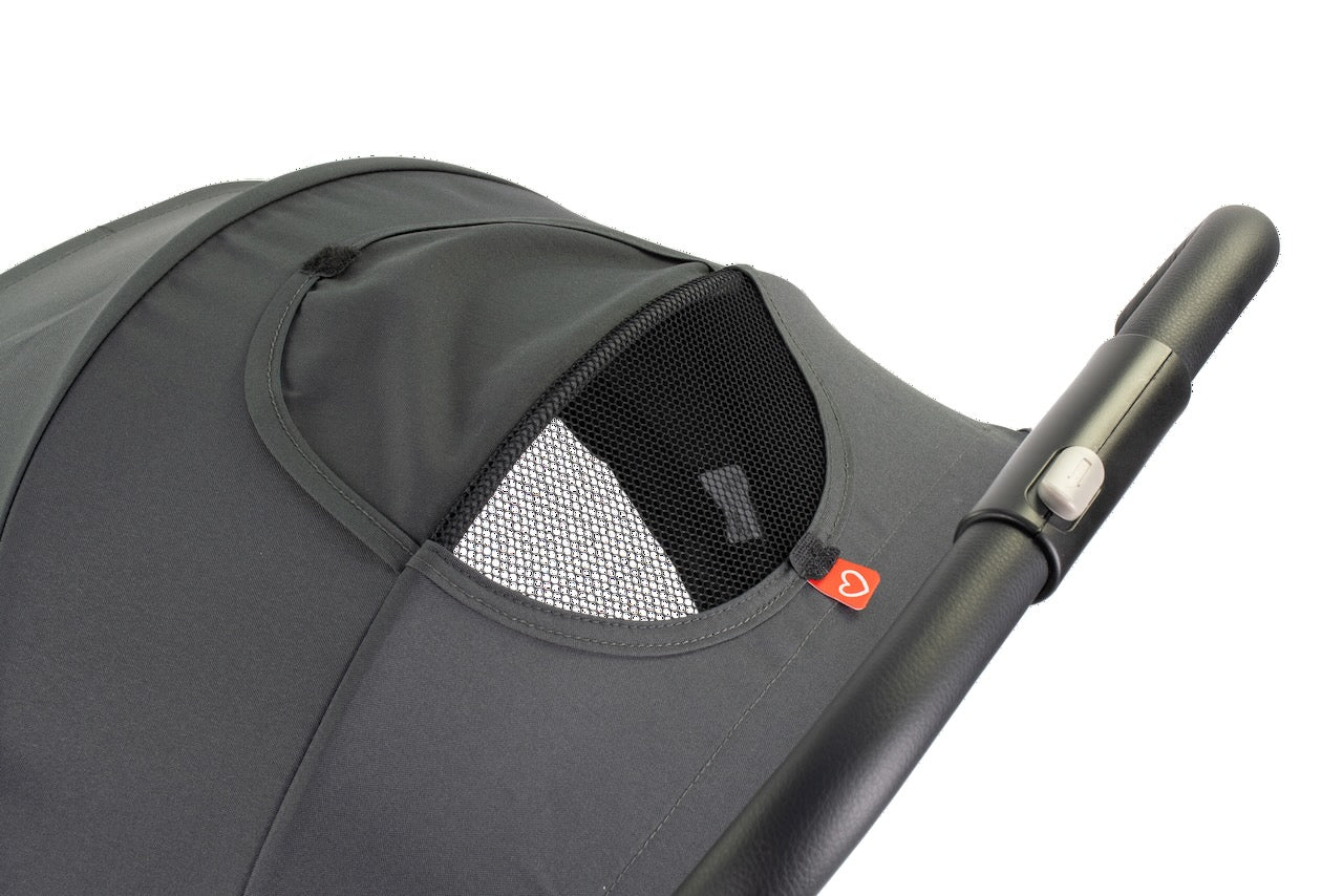 Close-up of a gray stroller with a mesh window and handle on a white background